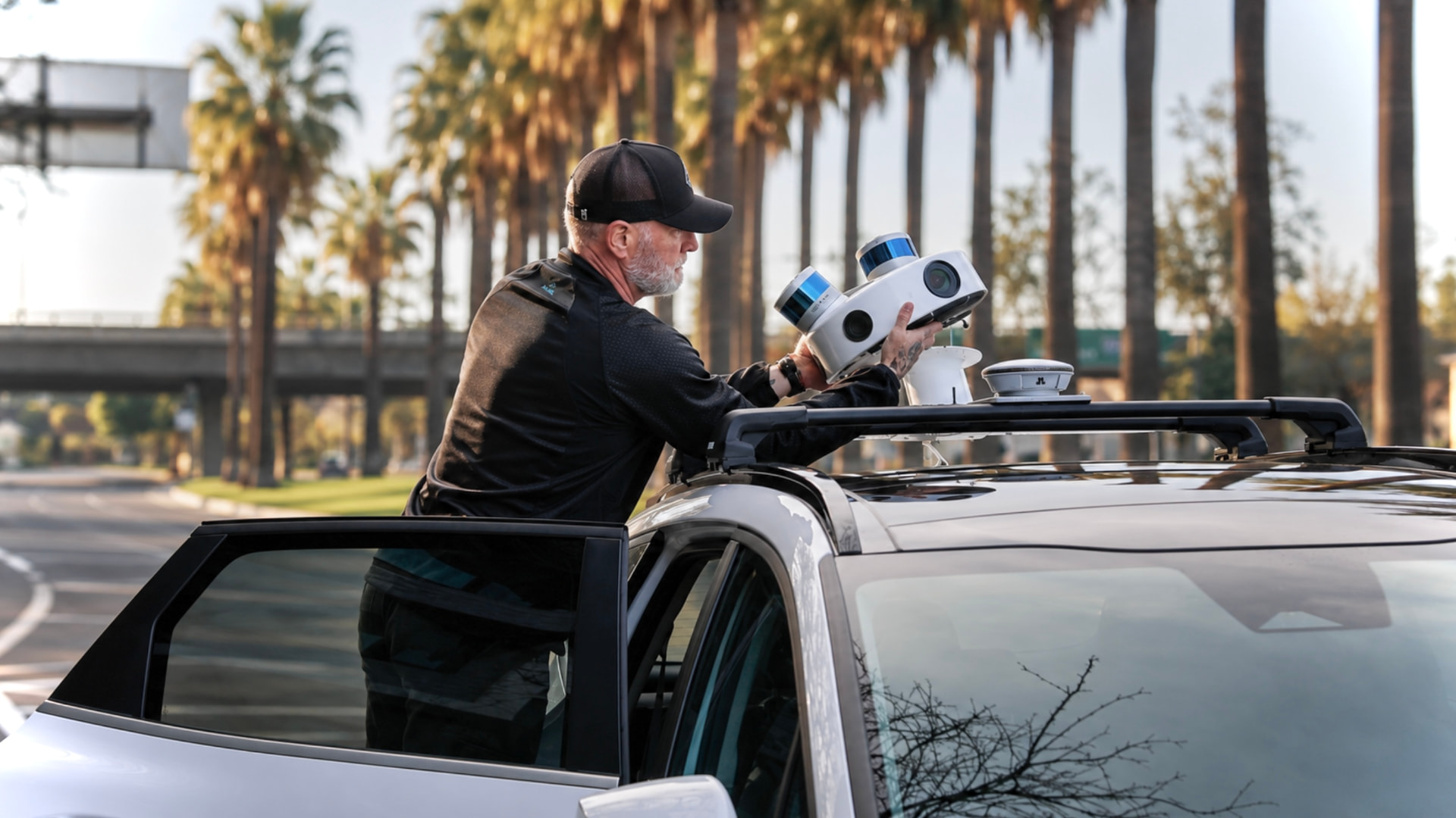 Technician installing multi-sensor scanning equipment on the roof of a SYMBO data collection vehicle